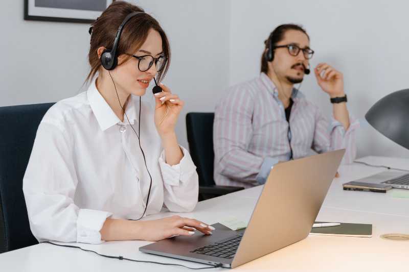 Imagem Ilustrativa - Há duas pessoas na foto, um homem e uma mulher. No entanto o foco está na mulher. Ele está fazendo um atendimento de remoto.